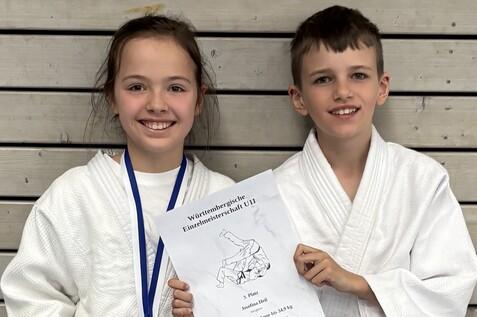 Zwei Kinder in Judojacken halten eine Urkunde für den 3. Platz bei der Württembergischen Einzelmeisterschaft U11.