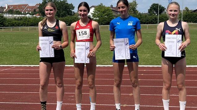 Vier Medaillengewinnerinnen stehen auf dem Siegerpodest, halten Urkunden und posieren bei sonnigem Wetter.