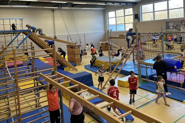 verschiedene Ger&auml;te in der Sporthalle sind aufgebaut. Kinder toben darauf