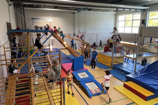 verschiedene Ger&auml;te in der Sporthalle sind aufgebaut. Kinder toben darauf