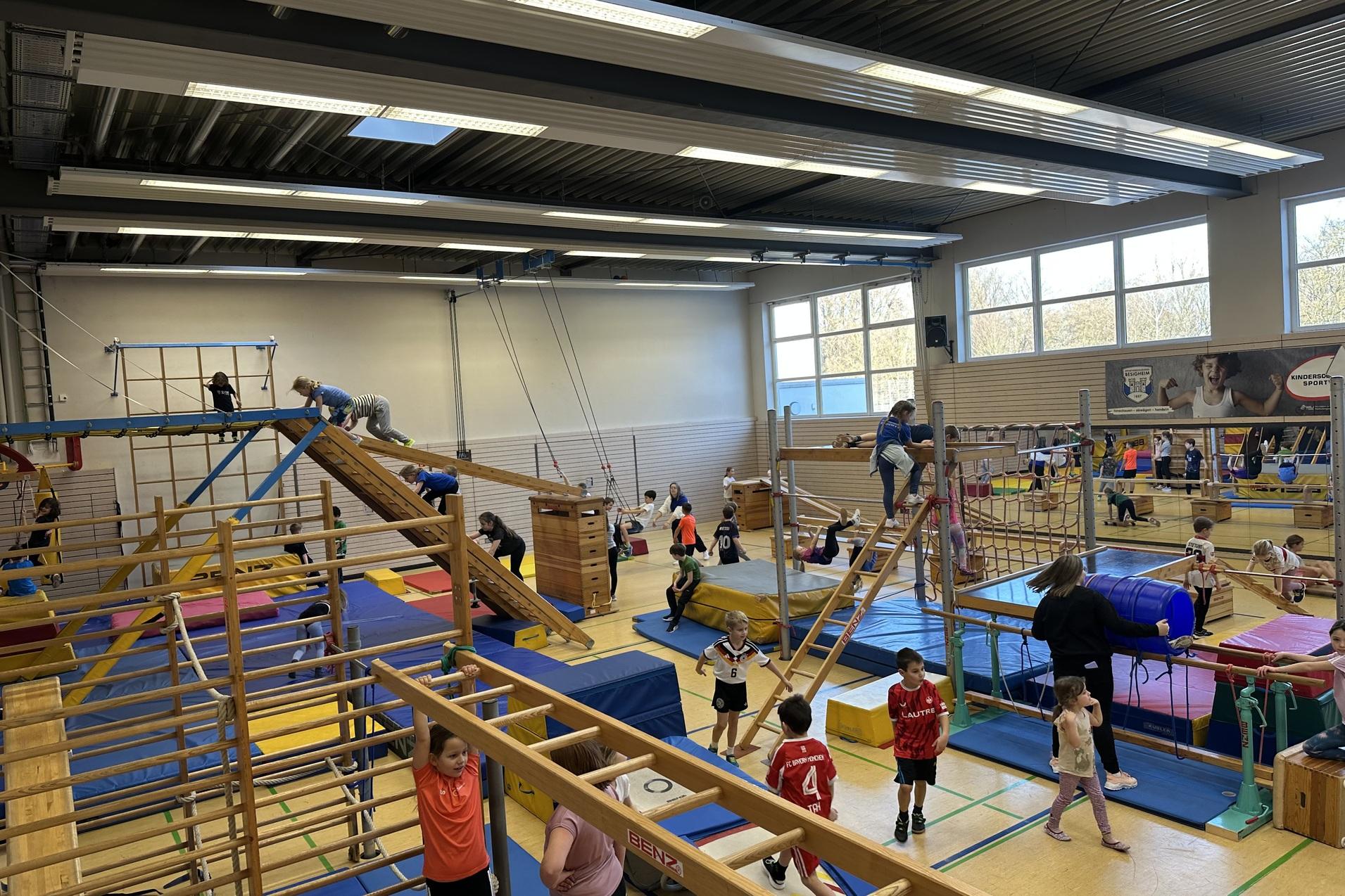 verschiedene Ger&auml;te in der Sporthalle sind aufgebaut. Kinder toben darauf
