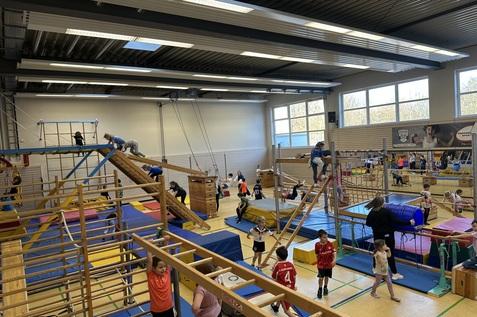 verschiedene Ger&auml;te in der Sporthalle sind aufgebaut. Kinder toben darauf