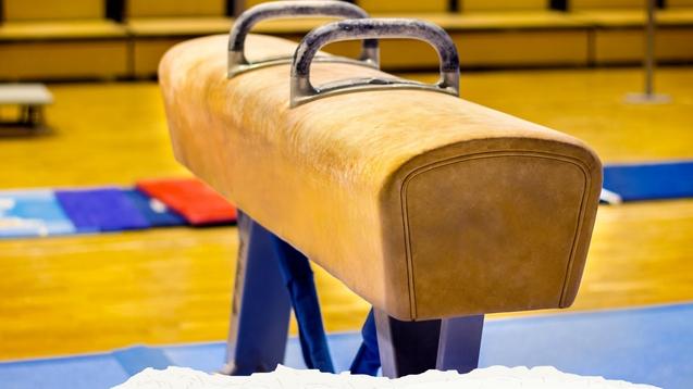 Nahaufnahme eines Turngeräts auf einem gymnasialen Boden mit Bewerbungsaufruf für einen Trainer im Gerätturnen.