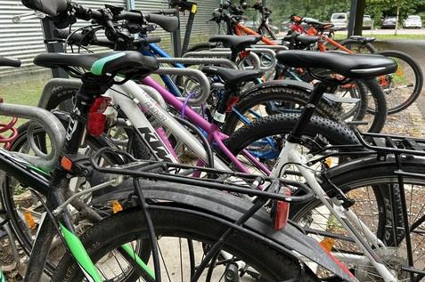 Bunte Fahrräder stehen in einem Fahrradständer, mit Fokus auf Details wie Sattel, Lenker und Räder.